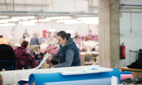 Kuvassa Black Moda Portugalin ompelimolla työntekijä isolla työpöydällä isojen neulorullien kanssa.