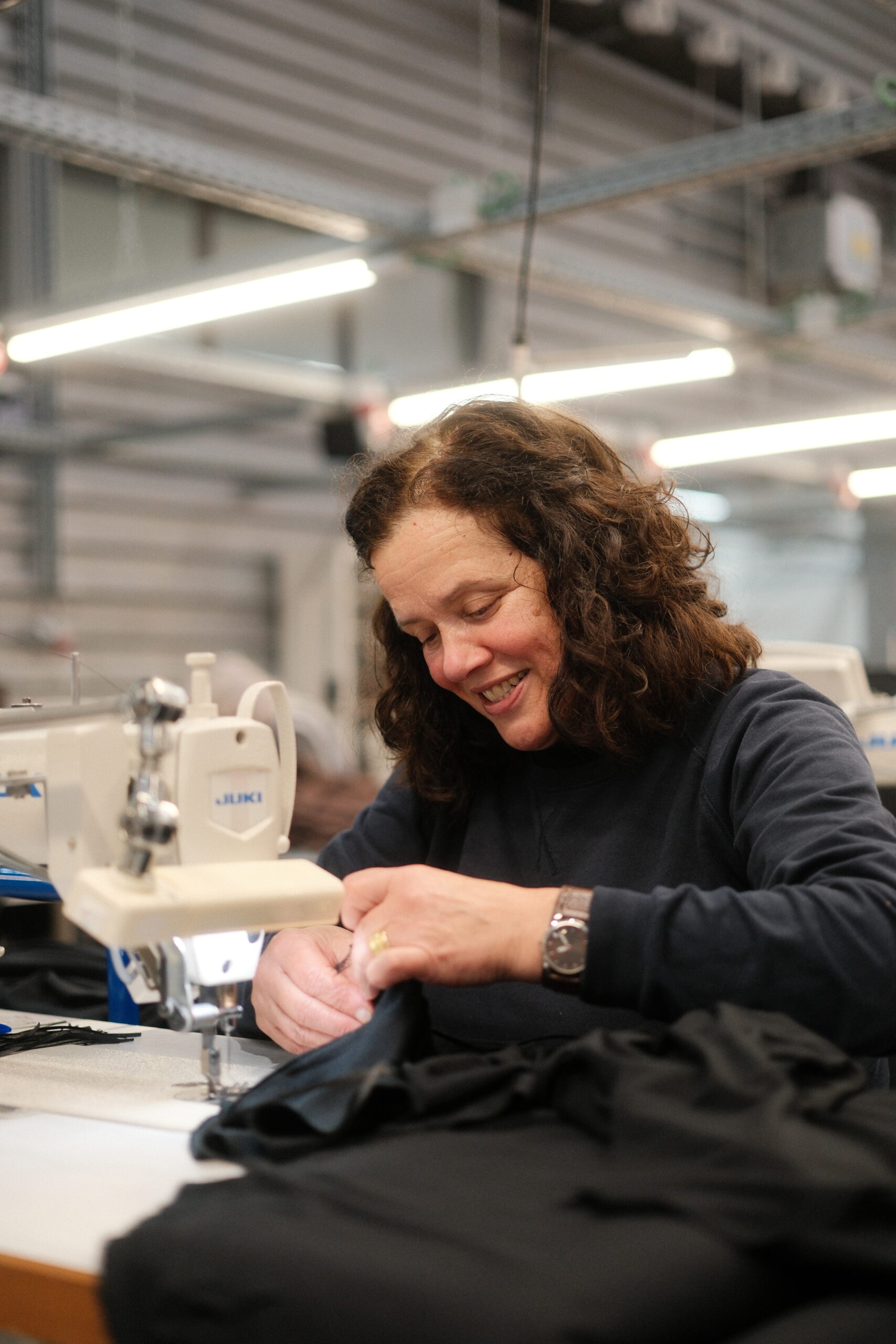Ompelija ompelemassa teollisuusompelikoneen ääressä mustaa vaatetta Black Moda Portugalin tehtaalla. 