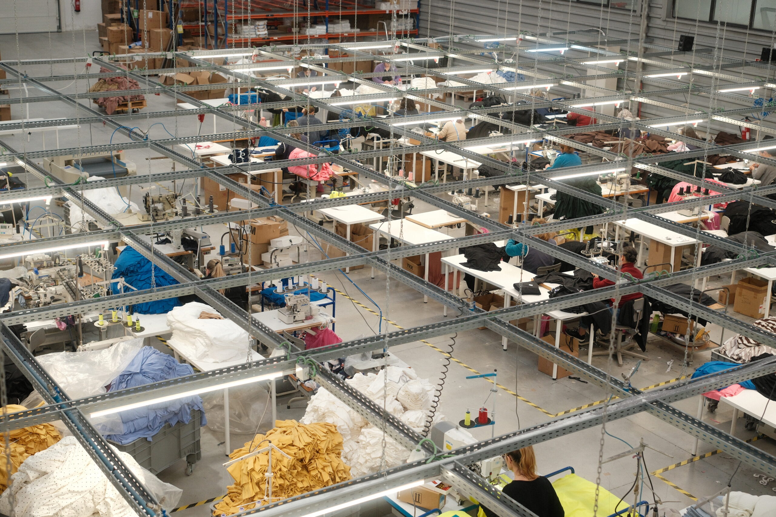 Black Moda Portugalin ompelusali, jossa paljon erilaisia ompelupisteitä, sekä kasoja leikatuista vaatteiden kappaleista. 